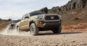 2018 Toyota Tacoma TRD Off-Road pulling a trailer over a dirt trail.