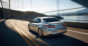A silver, 2018 Toyota Camry Hybrid driving down a highway.