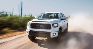 A white 2019 toyota tundra driving down a dusty road.