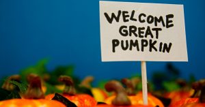 A sign saying "Welcome Great Pumpkin" posted in a pumpkin patch.