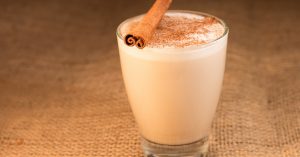 A warm glass of hot chocolate topped with a cinnamon stick.