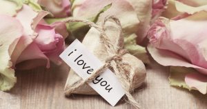 A lovely display with flowers and a heart tied with string bearing a note saying 'i love you'.