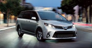 A silver 2020 Toyota Sienna parked in a street at night.