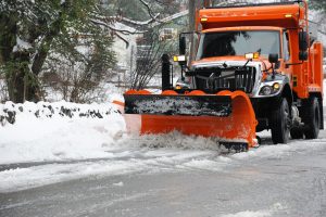 Orange snow plow removing snow from city streets