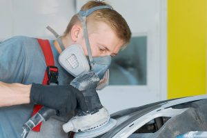 Body Shop Technician sanding vehicle.