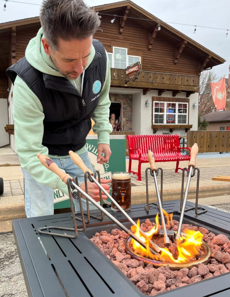 Man heating metal rods in a fire pit.