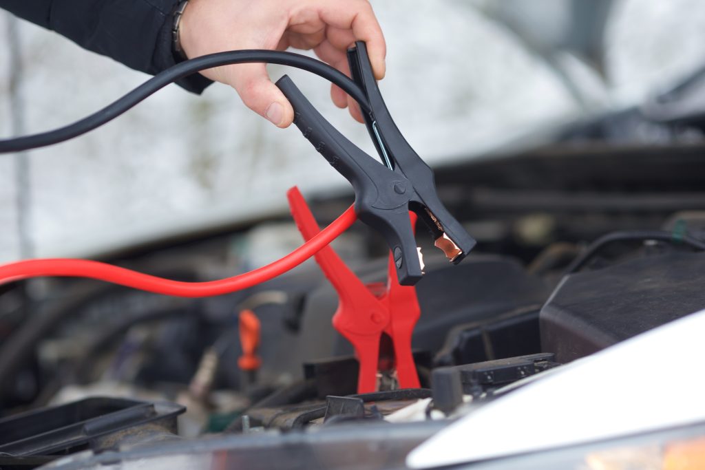 Black and red jumper cables being attached to a car battery
