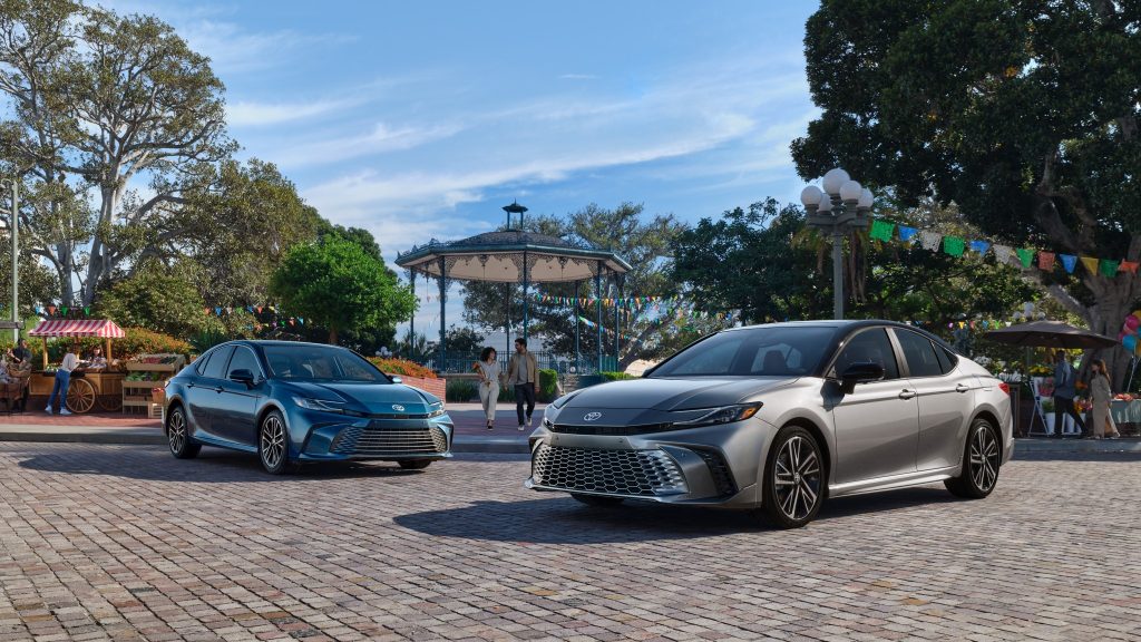 A blue and a gray 2025 Toyota Camry parked on a brick road.