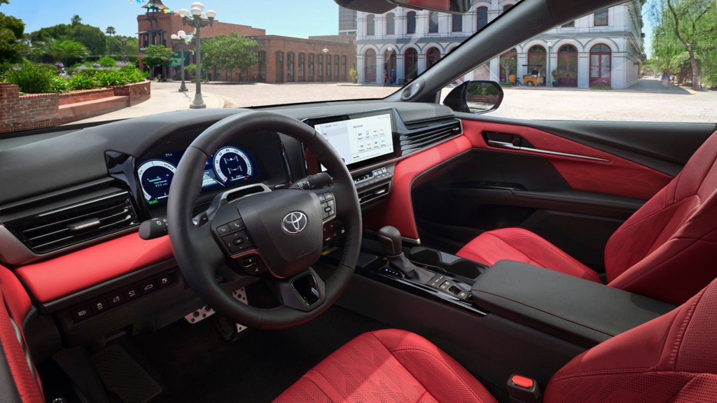 Interior of a 2025 Toyota Camry with red leather seats and touchscreen display on dashboard.