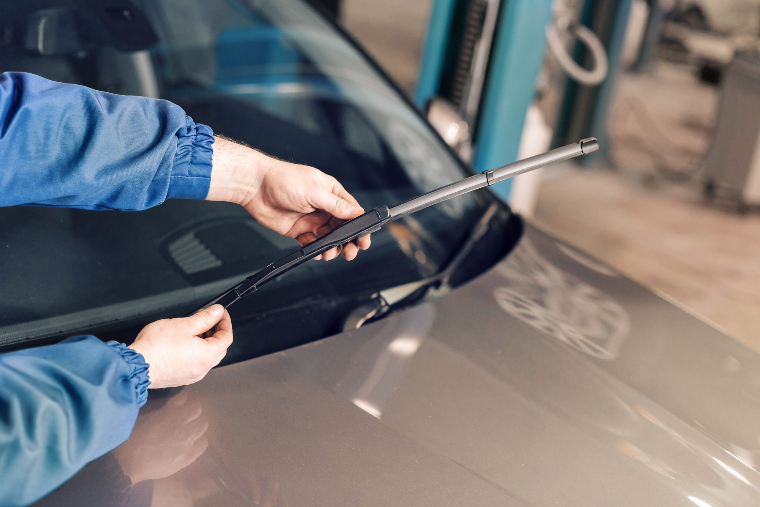 A man replacing windshield wipers on a vehicle.