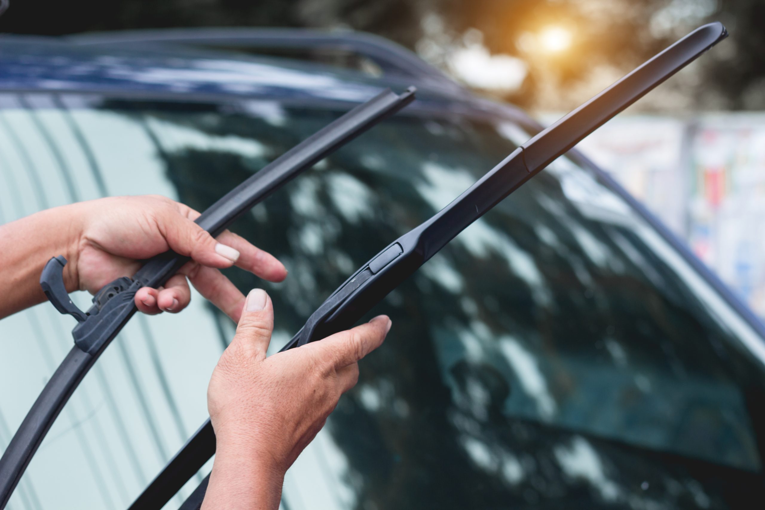 A technician replacing a car's windshield wipers