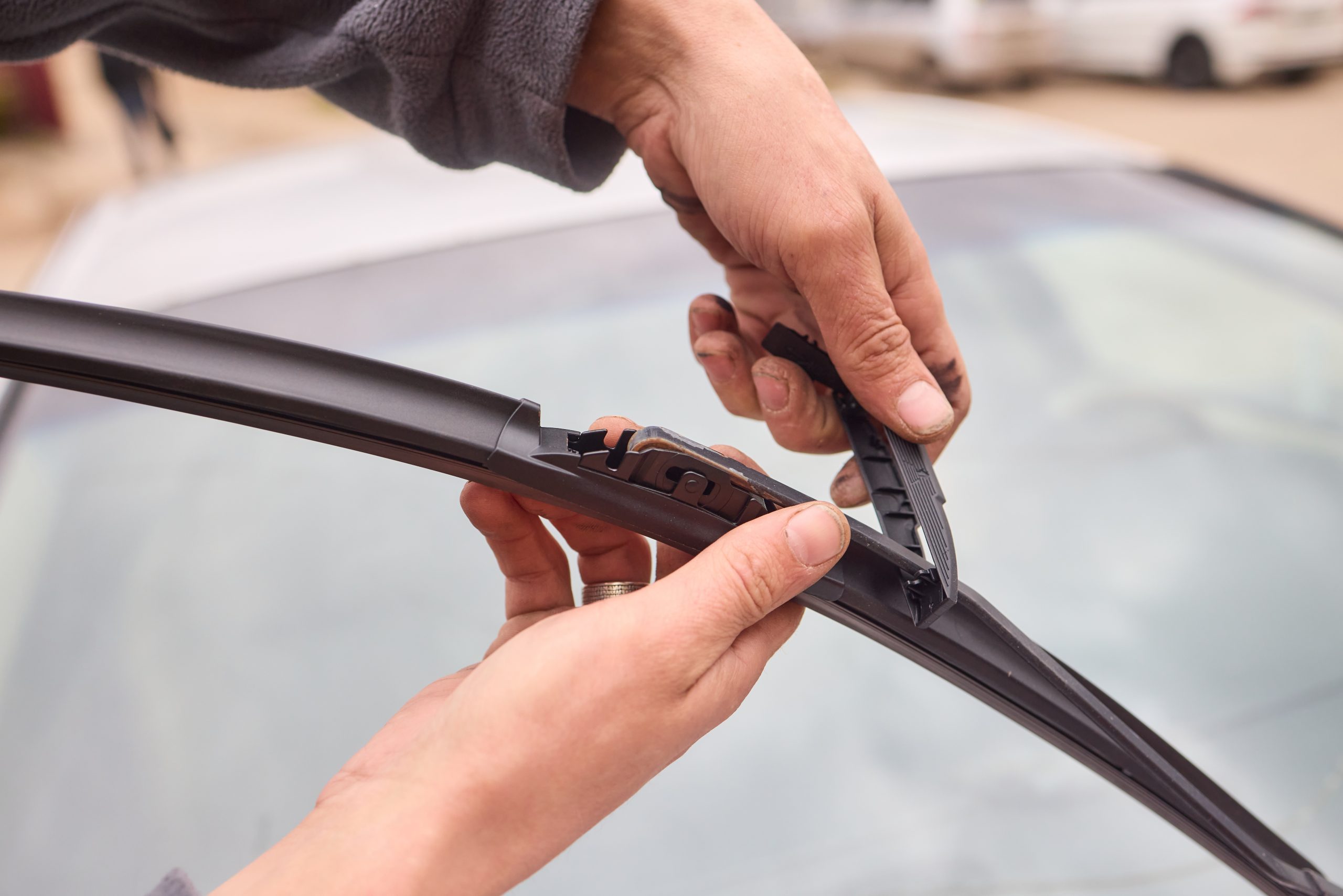 Person's hands checking windshield wipers.