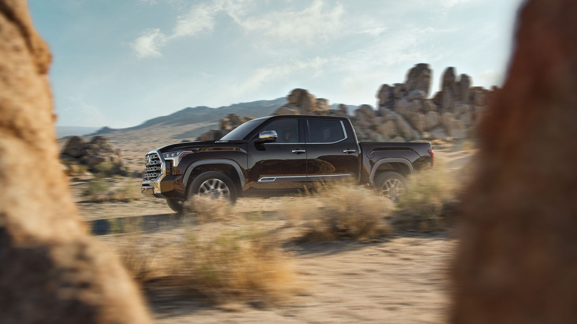 A black Toyota Tundra driving through a desert.