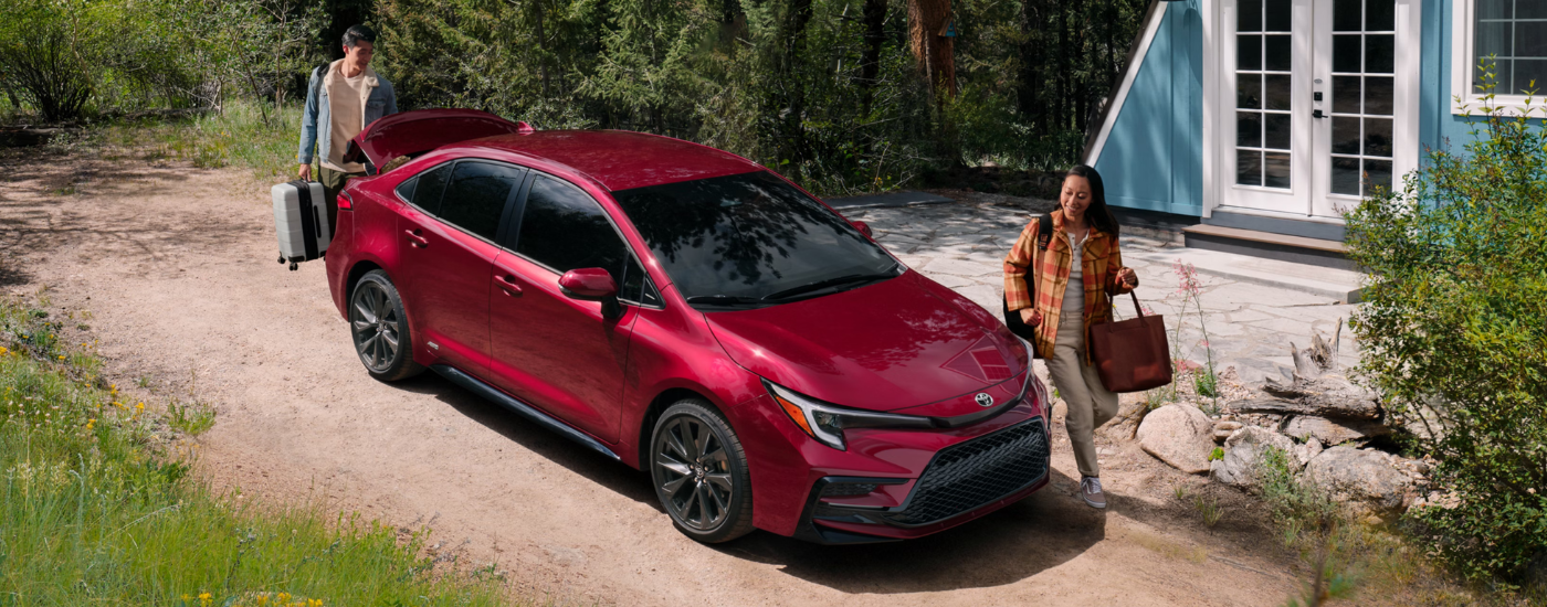 Two people packing a red 2026 Toyota Corolla