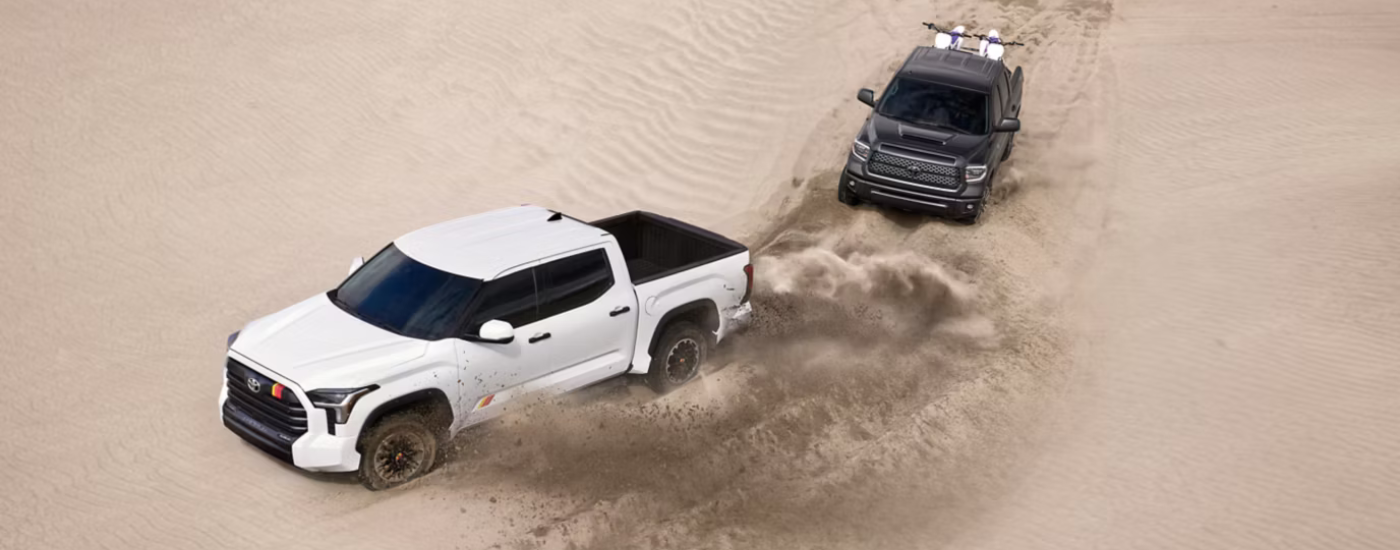 White 2026 Toyota Tundra TRD Rally driving through sand with a black 2026 Toyota Tundra following