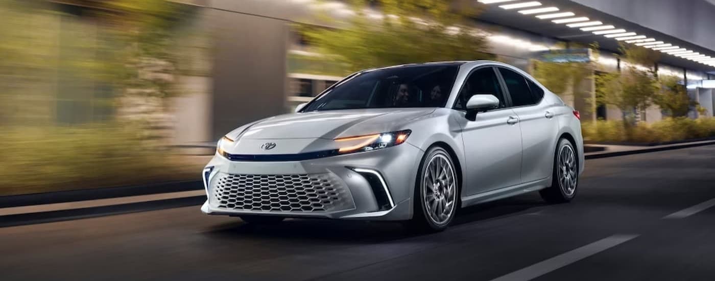 A silver 2025 Toyota Camry driving in a city.