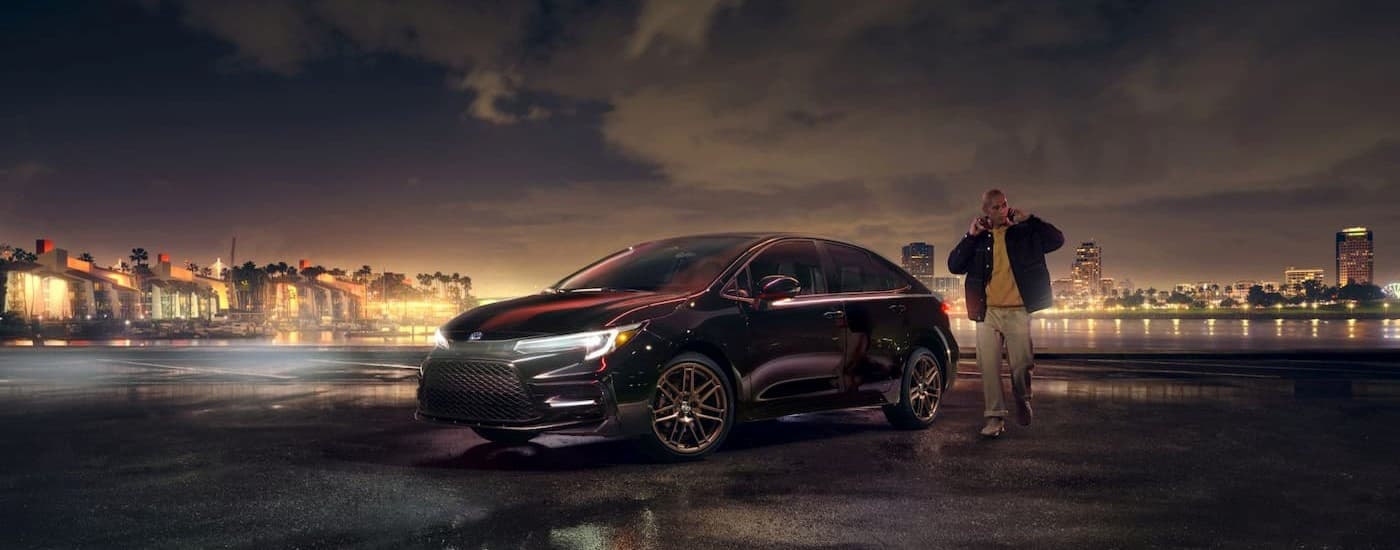 A person walking near a black 2024 Toyota Corolla.