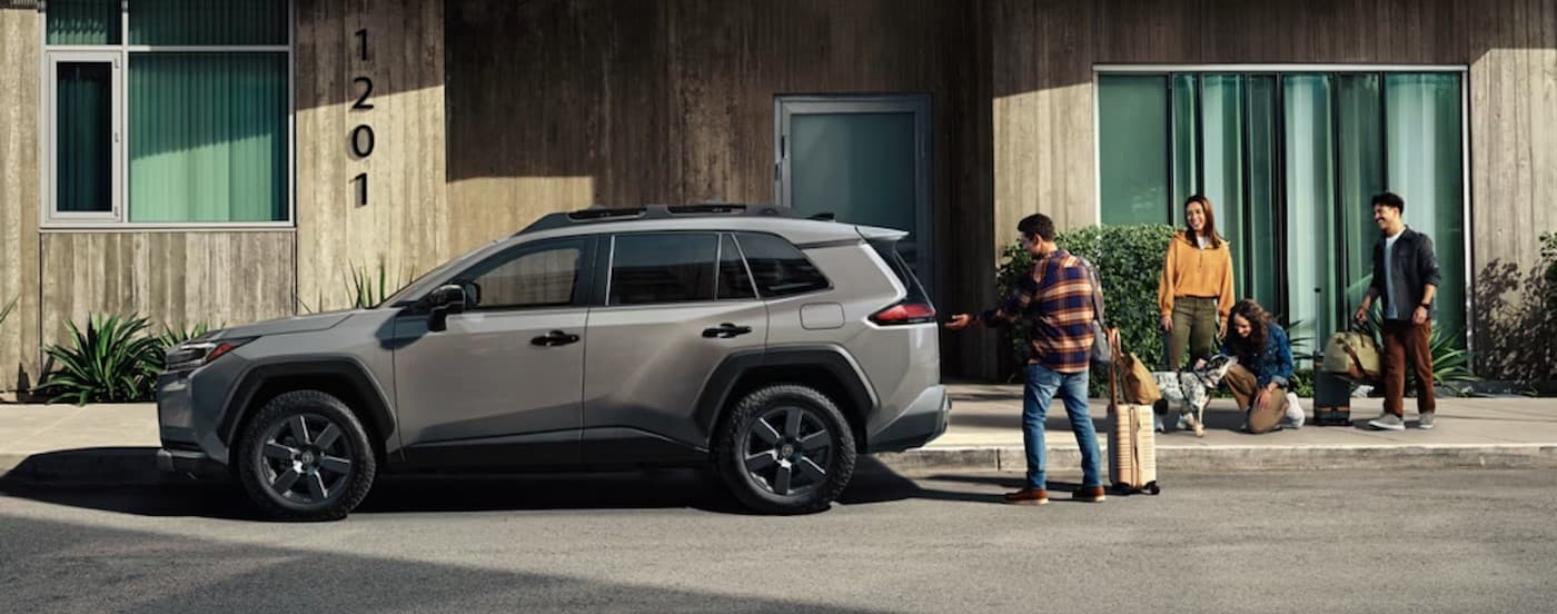 A gray 2026 Toyota RAV4 parked near a family.