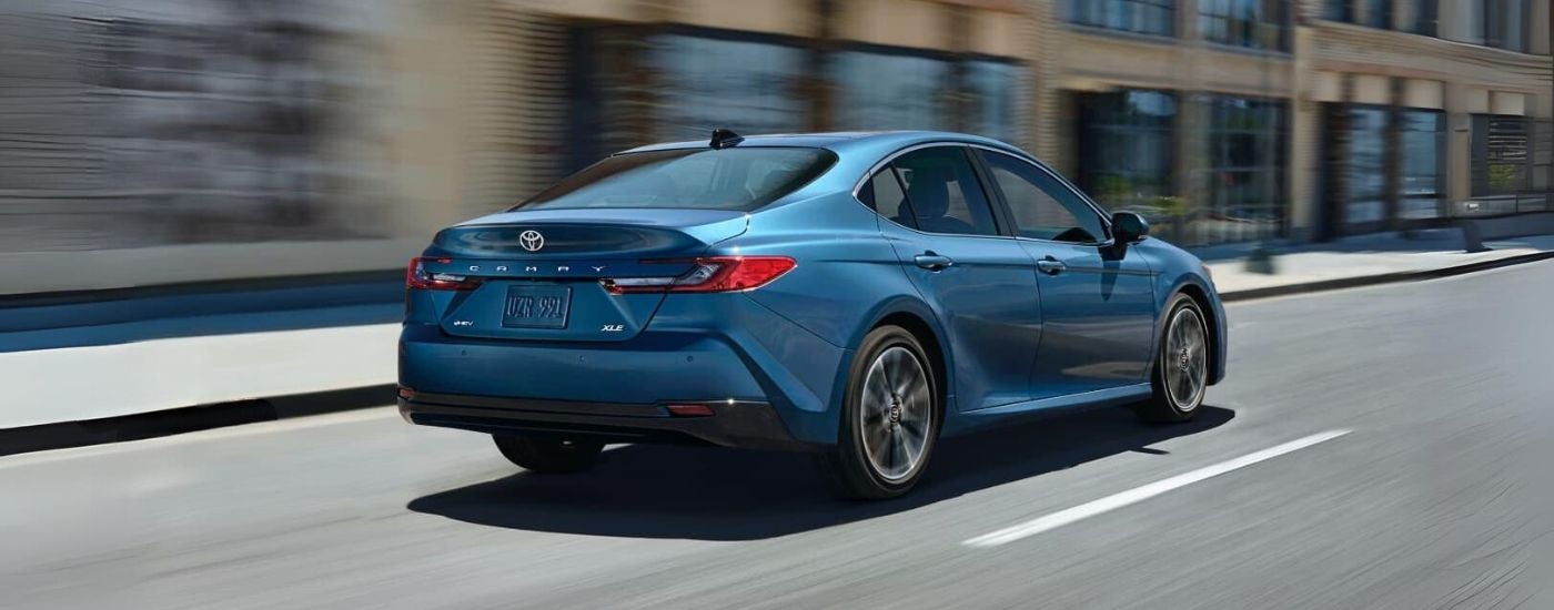 Blue 2025 Toyota Camry XLE driving down an open road from a Toyota dealer in Madison.