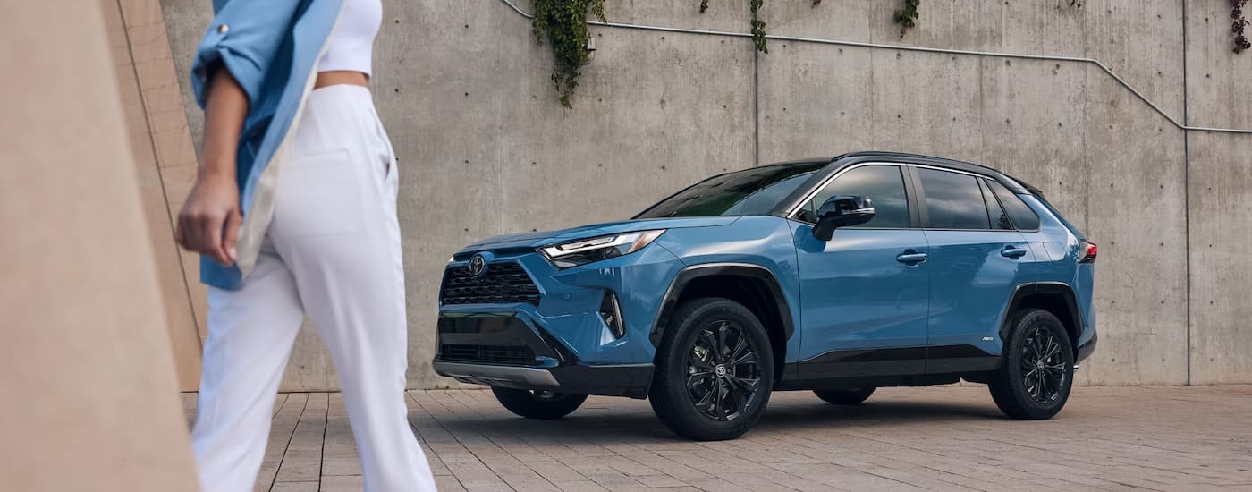 Blue 2025 Toyota RAV4 Hybrid for sale parked near a concrete wall
