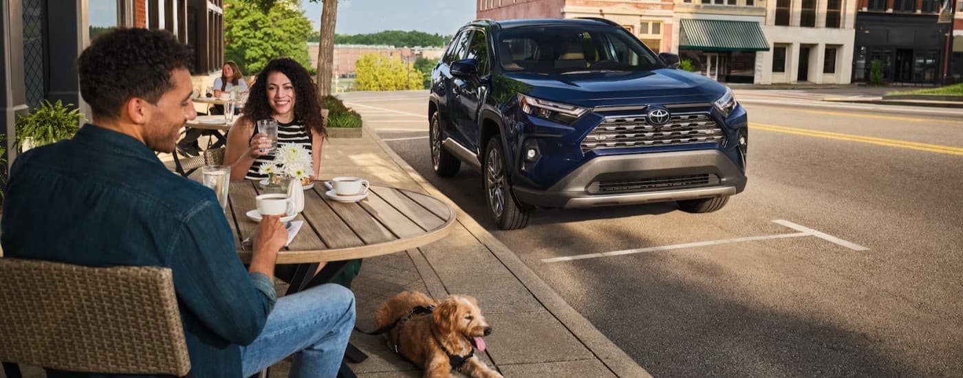 A blue 2026 Toyota RAV4 parked near a cafe.