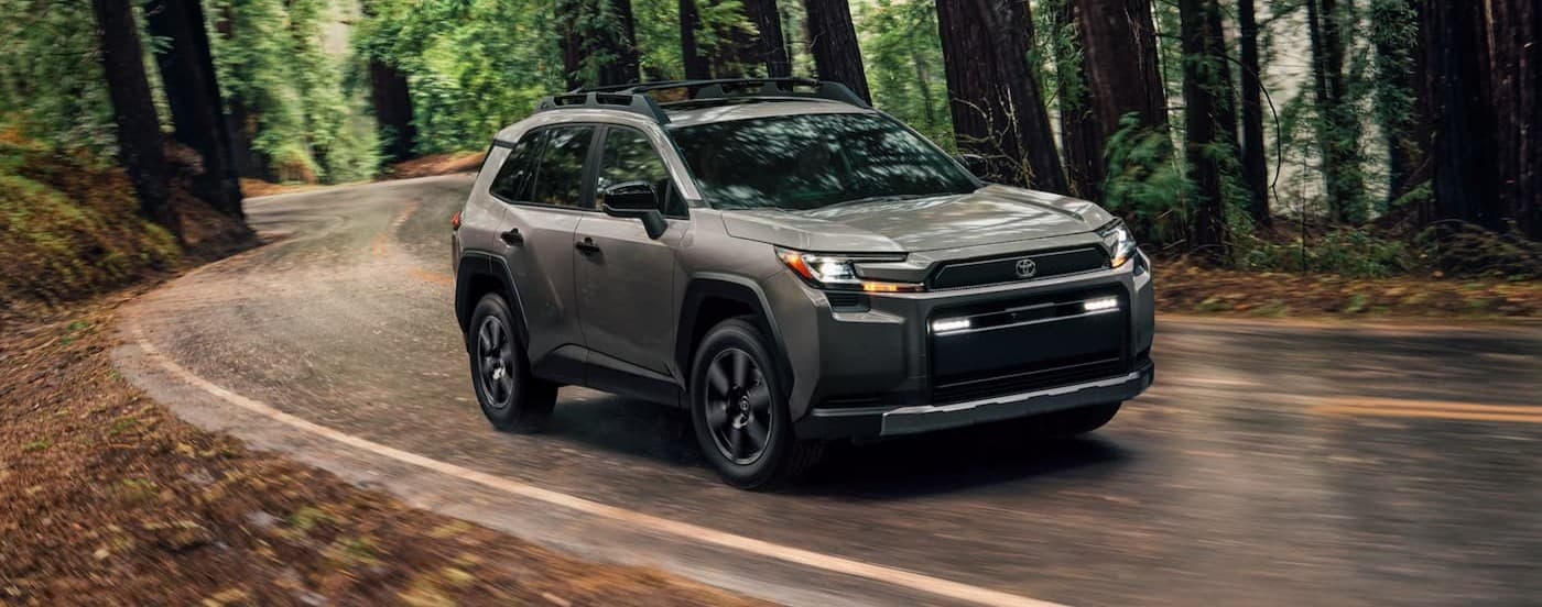 A gray 2025 Toyota RAV4 driving on a backroad.